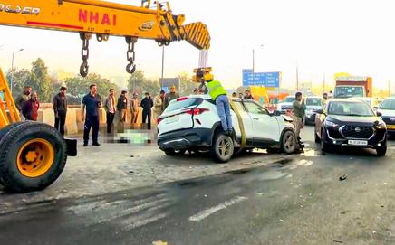 People gather as a crane picks up the wreckage of a car after it collided with a truck, in Ghazipur, New Delhi. Pic/PTI